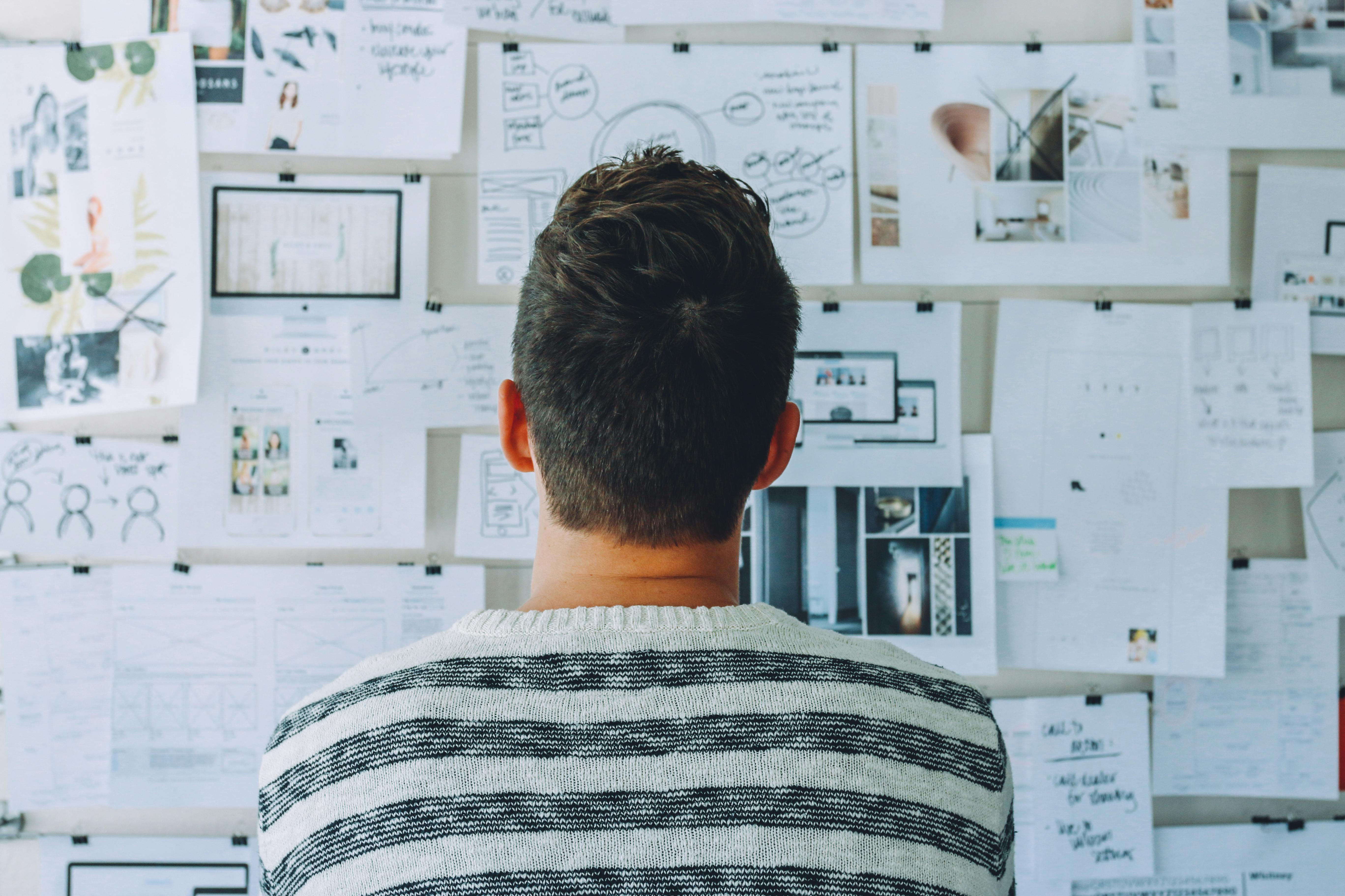 A worker planning a project, sitting in front of a board of ideas